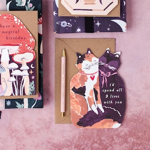 The perfect anniversary card or Valentines card for a cat lover, this uniquely shaped greeting card is cut into the shape of two snuggling cats. The adorable cat cards are blank on the inside, ready for a handwritten romantic message to be added