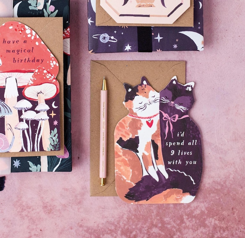 The perfect anniversary card or Valentines card for a cat lover, this uniquely shaped greeting card is cut into the shape of two snuggling cats. The adorable cat cards are blank on the inside, ready for a handwritten romantic message to be added