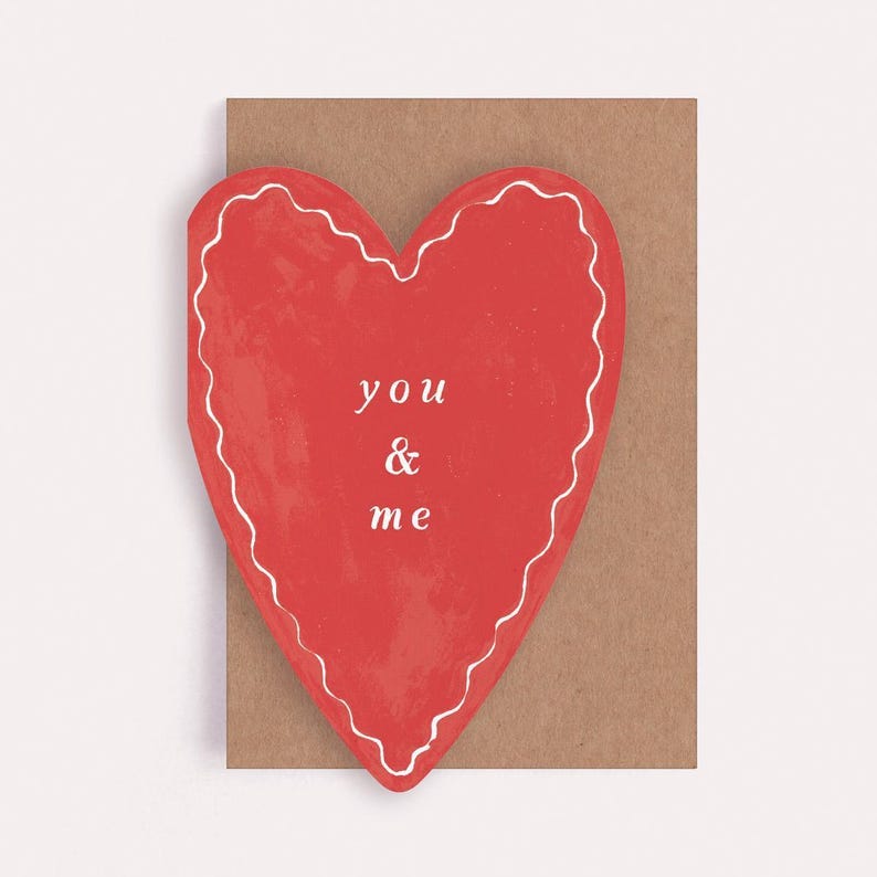 A heart shaped valentines card with the caption you and me plus a brown kraft envelope.