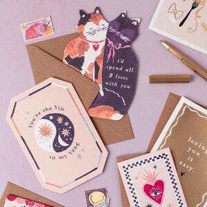 The perfect anniversary card or Valentines card for a cat lover, this uniquely shaped greeting card is cut into the shape of two snuggling cats. The adorable cat cards are blank on the inside, ready for a handwritten romantic message to be added