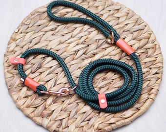 May include: A dark green rope dog lead with orange accents and a copper clasp. The lead is coiled on a woven straw mat.
