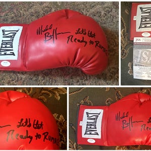 Puede incluir: Un guante de boxeo rojo Everlast con texto negro que dice "Mike B" y "Let's Get Ready to Rumble". El guante tiene un parche blanco con el logotipo de Everlast. También es visible un certificado de autenticidad.