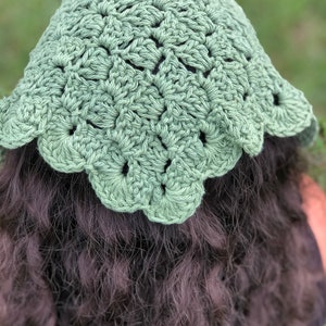 Puede incluir: Un sombrero de ganchillo verde salvia con un borde festoneado. El sombrero est&aacute; hecho de un hilo texturizado y tiene un dise&ntilde;o calado detallado. El sombrero se muestra desde atr&aacute;s, con cabello oscuro visible debajo.