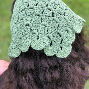 Puede incluir: Un gorro de ganchillo verde salvia con un borde festoneado. El tocado hecho a mano est&aacute; hecho de un hilo suave y se muestra en una persona con cabello casta&ntilde;o oscuro. El gorro es un accesorio elegante.