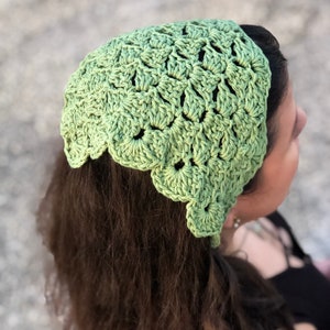 Puede incluir: Una diadema de ganchillo verde claro con un borde festoneado. La diadema est&aacute; hecha de un hilo texturizado y se usa en la cabeza. La imagen es un primer plano de la diadema y la parte posterior de la cabeza de una persona.
