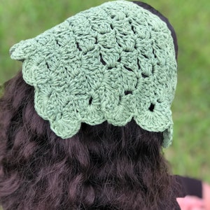 Puede incluir: Un gorro de ganchillo verde claro con un borde festoneado. El tocado hecho a mano est&aacute; hecho de un hilo texturizado y se muestra desde atr&aacute;s, con cabello oscuro visible debajo de la gorra. El gorro es de un color verde suave y apagado.