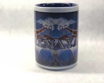 Puede incluir: Una taza de cerámica blanca con un borde azul y una imagen azul y blanca de una palmera con el texto "YEMA YA" impreso en la parte delantera.
