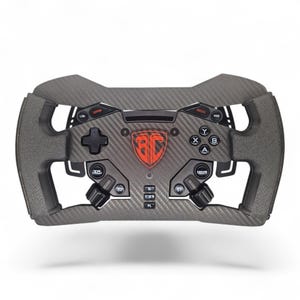 May include: A grey and black racing wheel with various buttons, knobs, and a directional pad. The centre features a red logo. The wheel has a carbon fibre texture and is designed for gaming.