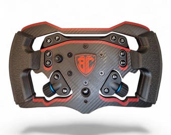 May include: A black and red carbon fiber racing steering wheel controller featuring a central shield logo with the letters BC, multiple labeled buttons including X, Y, A, B, LT, RT, LSB, RSB, GL, GR, and two small blue-accented rotary dials.