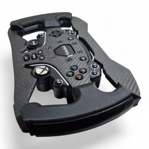 以下が含まれることがあります： 中央にMoza Racingのロゴが入った黒いカーボンファイバー製レーシングステアリングホイールコントローラー。Xboxボタン、A、B、X、Yボタン、各種方向入力、側面にテクスチャ加工されたグリップを備えており、ゲームプレイに使用されます。