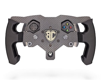 May include: A carbon fiber racing steering wheel controller featuring black ergonomic grips, a central shield emblem with the letters BC, a directional pad, and four colored action buttons labeled X, Y, A, and B, with an Xbox logo at the bottom.