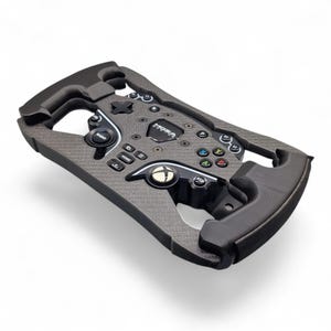 May include: A black carbon fiber racing steering wheel controller featuring a central Moza logo, an Xbox button, and various labeled buttons including Radio, Home, and directional inputs. The device has a rectangular frame with ergonomic grips.