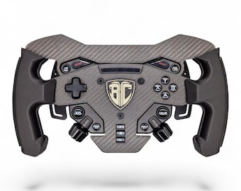 May include: A carbon fiber textured racing steering wheel controller featuring black ergonomic grips, a central shield logo with the letters BC, a D-pad, four action buttons labeled A, B, X, Y, and various rotary dials and toggle switches.