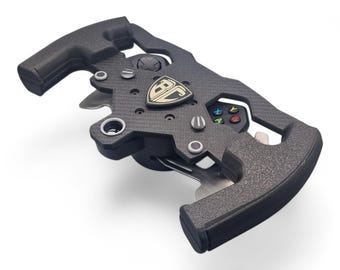 May include: A black racing steering wheel controller featuring a carbon fiber texture, a central shield emblem with the letters BC, integrated gaming buttons including a D-pad, and four colored action buttons labeled A, B, X, and Y on the right side.