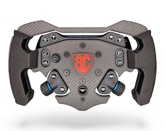 May include: A black and gray carbon fiber racing steering wheel controller featuring a central red shield logo with the letters BC. The device includes multiple buttons labeled A, B, X, Y, LT, RT, LSB, RSB, GL, GR, and GT, along with two side grips.