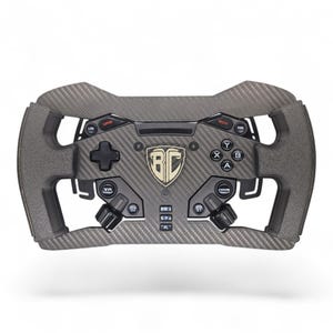 May include: A grey and black racing wheel with a carbon fibre design. It features multiple buttons, dials, and a central emblem. The wheel has a rectangular shape with cutouts on the sides, designed for sim racing.