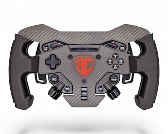 May include: A black and dark gray carbon fiber racing steering wheel controller featuring a central red shield logo with the letters BC. The device includes a directional pad, A, B, X, Y buttons, multiple toggle switches, and rotary dials.