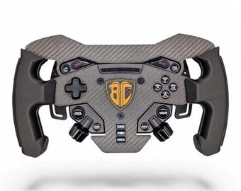 May include: A racing steering wheel controller featuring a dark gray carbon fiber textured faceplate, black ergonomic side grips, and a central shield-shaped emblem with the letters BC in orange. It includes various buttons, a D-pad, and knobs.