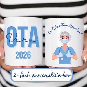 Könnte beinhalten: Zwei weiße Keramikbecher mit blauem Text und Grafiken. Auf einem Becher steht "OTA Vera 2026". Der andere Becher zeigt eine Cartoon-Krankenschwester und den Text "Ich liebe offene Menschen!".