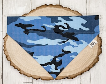 May include: Blue and black camouflage bandana for a pet. The bandana is on a wooden surface.
