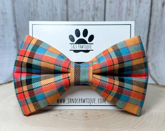 May include: Orange, blue, and black plaid bow tie with a white card behind it that says "J&S Pawtique" and "www.jandspawtique.com".