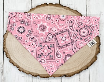 Può includere: Bandana rosa con un motivo paisley bianco e nero. La bandana è su una superficie di legno.