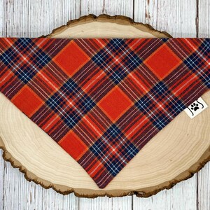May include: Orange, blue, and white plaid dog bandana with a paw print logo.