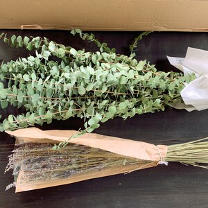 May include: Two bundles of dried flowers, one bundle of eucalyptus in white paper and one bundle of lavender in brown paper.