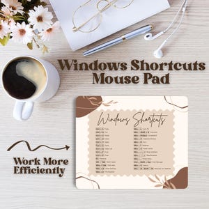Könnte beinhalten: Beige Mauspad mit Windows-Shortcuts und dem Text „Work More Efficiently“. Das Pad hat ein braunes Dekor. Eine Kaffeetasse, eine Brille, ein Stift und Kopfhörer befinden sich ebenfalls auf dem Schreibtisch.
