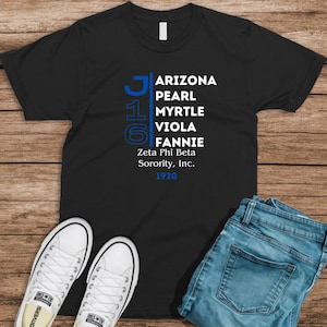 May include: Black t-shirt with white text that reads "Arizona Pearl Myrtle Viola Fannie Zeta Phi Beta Sorority, Inc. 1920".