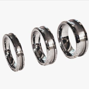 May include: Three silver rings with a grooved design. The rings are displayed on a white background, showcasing their polished metal finish. The grooves create a textured appearance, adding visual interest to the jewelry.