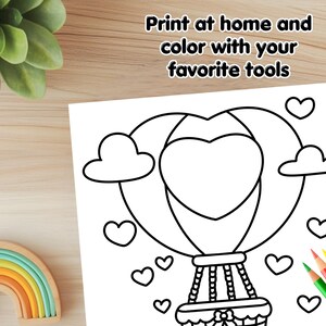 May include: A black and white coloring page featuring a hot air balloon shaped like a heart with clouds and hearts around it. The text "Print at home and color with your favorite tools" is at the top of the page.