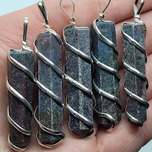 May include: Five silver wire wrapped crystal pendants. The crystals are dark blue with iridescent flecks and have a pointed shape. The wire wraps are silver and spiral around the crystals.