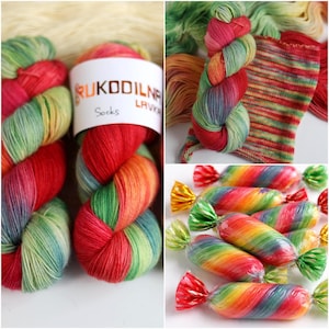 May include: A collage of colorful yarn and candies. The yarn is a mix of red, green, and yellow, with a label that reads "RUKODILNA LAVKA Socks." The candies are wrapped in clear cellophane with red, green, and yellow twist ends.