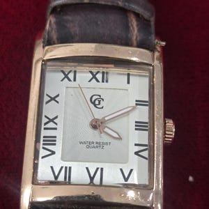 May include: A white ceramic mug with a black handle and the text "But First, Coffee" in a handwritten style. The mug is on a white surface. The mug is approximately 4 inches tall.