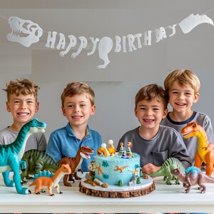 May include: Four boys celebrate a birthday with a dinosaur-themed cake. The cake is decorated with dinosaurs and has a blue frosting. The boys are smiling and holding dinosaur toys. A banner with the words "Happy Birthday" hangs above them.