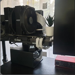 May include: A custom computer build featuring a black MSI GeForce RTX graphics card with white power cables, a dual-fan Noctua Chromax CPU cooler, and a small digital display showing 47°C and 24°C. A small artificial succulent in a white pot sits on top.