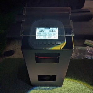 May include: A black and silver device with a digital display showing the text "EYEMINI" and the following readings: -RH 100, 83.6, 7253, 3776L, 7.5°R, 30.7, 1.22, 68.5, 16.9°, -1.1°.