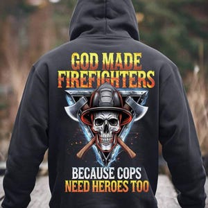Può includere: Felpa con cappuccio nera con una stampa grafica di uno scheletro che indossa un casco da pompiere e asce incrociate. Il testo recita "God Made Firefighters Because Cops Need Heroes Too."