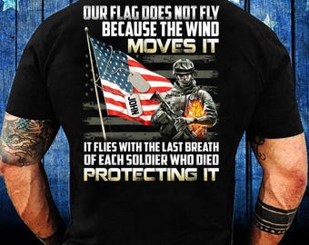 Może przedstawiać: Czarna koszulka z grafiką amerykańskiej flagi, żołnierza i napisem "OUR FLAG DOES NOT FLY BECAUSE THE WIND MOVES IT. IT FLIES WITH THE LAST BREATH OF EACH SOLDIER WHO DIED PROTECTING IT."