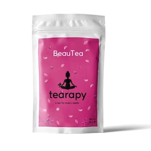 May include: A pink pouch with the text "BeauTea tearapy a tea for every needs" and a silhouette of a person sitting in a yoga pose. The pouch has a white background and a pink design with white petals. The text "Net wt. 90 g e" is printed on the bottom right corner of the pouch.