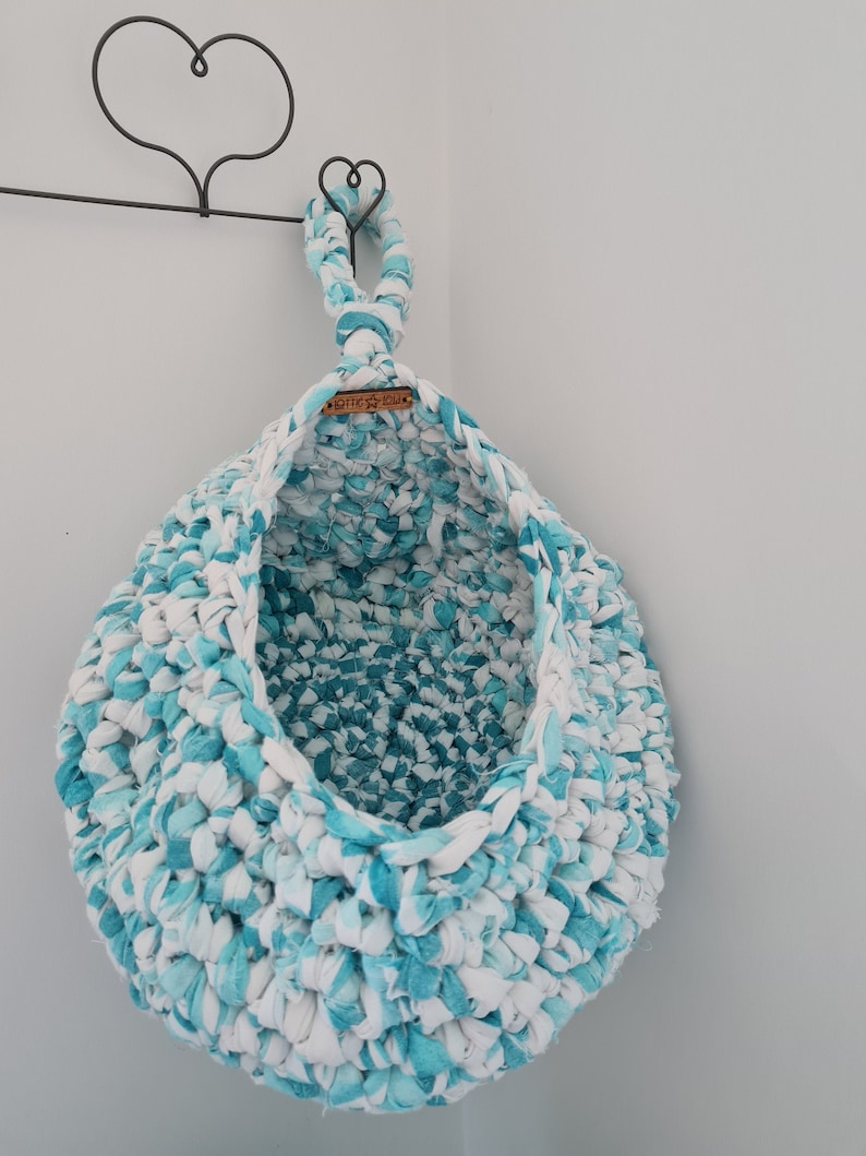 May include: A teal and white crocheted hanging basket with a wooden tag that says "Little You".
