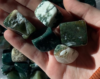 May include: A collection of green and white agate tumbled stones. The stones are smooth and polished, with a variety of patterns and textures.