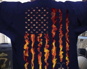 May include: A navy blue t-shirt with a fiery American flag design and the word "WELDER" printed below. The flag is made up of flames and has two welding torches crossed underneath.
