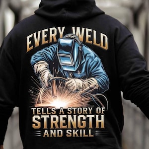 Könnte beinhalten: Schwarzer Kapuzenpullover mit einem Grafikdruck eines Schweißers mit Schweißmaske und Funkenflug. Der Text "Every Weld Tells A Story Of Strength And Skill" ist auf dem Pullover aufgedruckt.