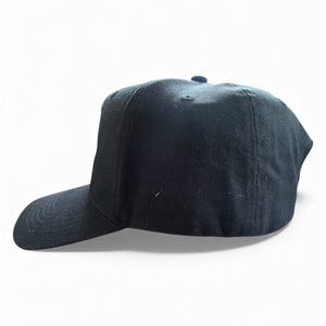 K&ouml;nnte beinhalten: Einfarbige schwarze Baseballkappe mit gebogenem Schirm. Die Kappe hat eine strukturierte Krone und einen kleinen Knopf oben. Hergestellt aus strapazierf&auml;higem Stoff, geeignet f&uuml;r den t&auml;glichen Gebrauch.