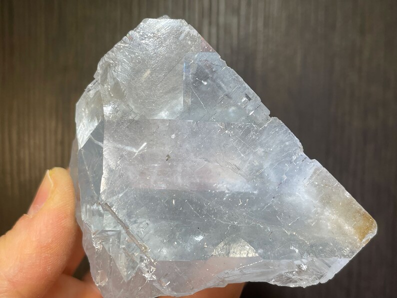 K&ouml;nnte beinhalten: Ein gro&szlig;er, durchscheinender, hellblauer Kristall mit einer rauen, facettierten Oberfl&auml;che. Der Kristall hat eine geometrische Form mit sichtbaren inneren Strukturen und einem leichten Gelbstich an einer Kante. Das Gesamtbild ist kristallin und nat&uuml;rlich.