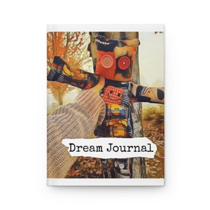 May include: A Dream Journal notebook with a colorful, patchwork doll design on the cover. The doll has button eyes and a stitched smile. The words "Dream Journal" are printed in a simple font.