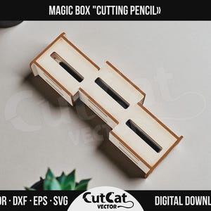 以下が含まれることがあります： 「MAGIC BOX 'CUTTING PENCIL'」の文字が上部にある、木製のカッティングペンシル用マジックボックス。ボックスは明るい茶色のフレームと、3つの長方形のスロットを備えた白い内装です。画像の下部には「AI • CDR • DXF • EPS • SVG CutCat VECTOR DIGITAL DOWNLOAD」と書かれています。