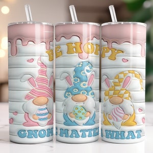 May include: Three pastel-colored Easter gnome tumblers with pink, blue, and yellow gnomes holding Easter eggs. The tumblers have a white background with a woodgrain pattern and the text "Be Hoppy Gnome Matter What".